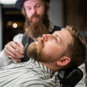 Focused barber prepares to shave a bearded client in a stylish barbershop setting.
