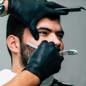 Close-up of a barber shaving a man's beard with precision in a contemporary barbershop setting.